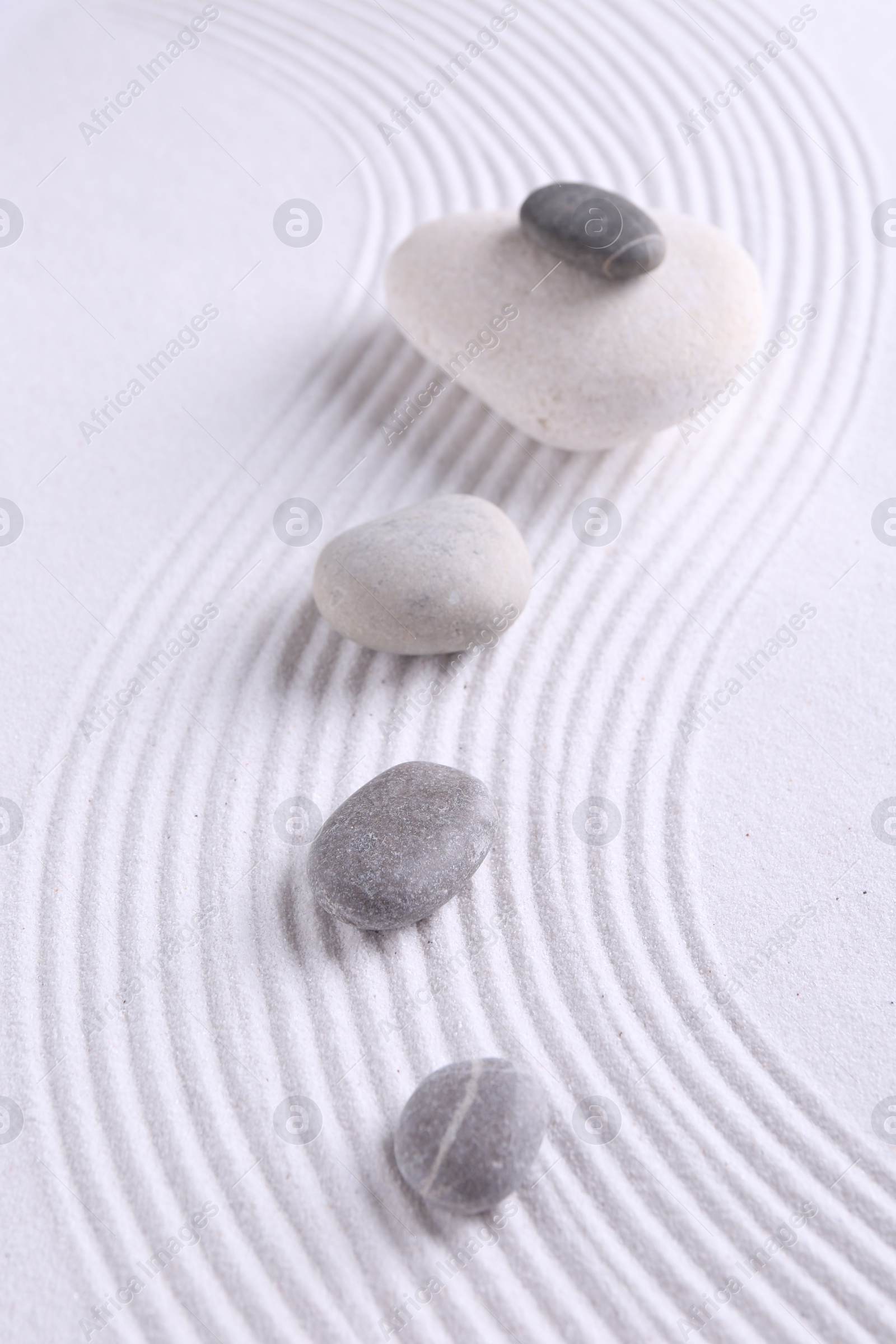 Photo of Zen garden stones on white sand with pattern