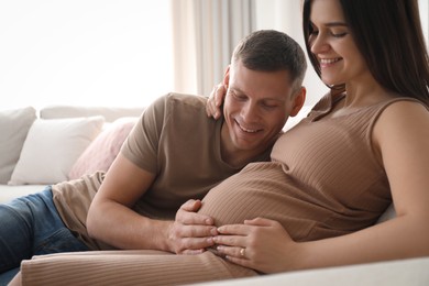 Photo of Man touching his pregnant wife's belly at home