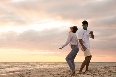 Photo of Happy couple dancing on beach at sunset