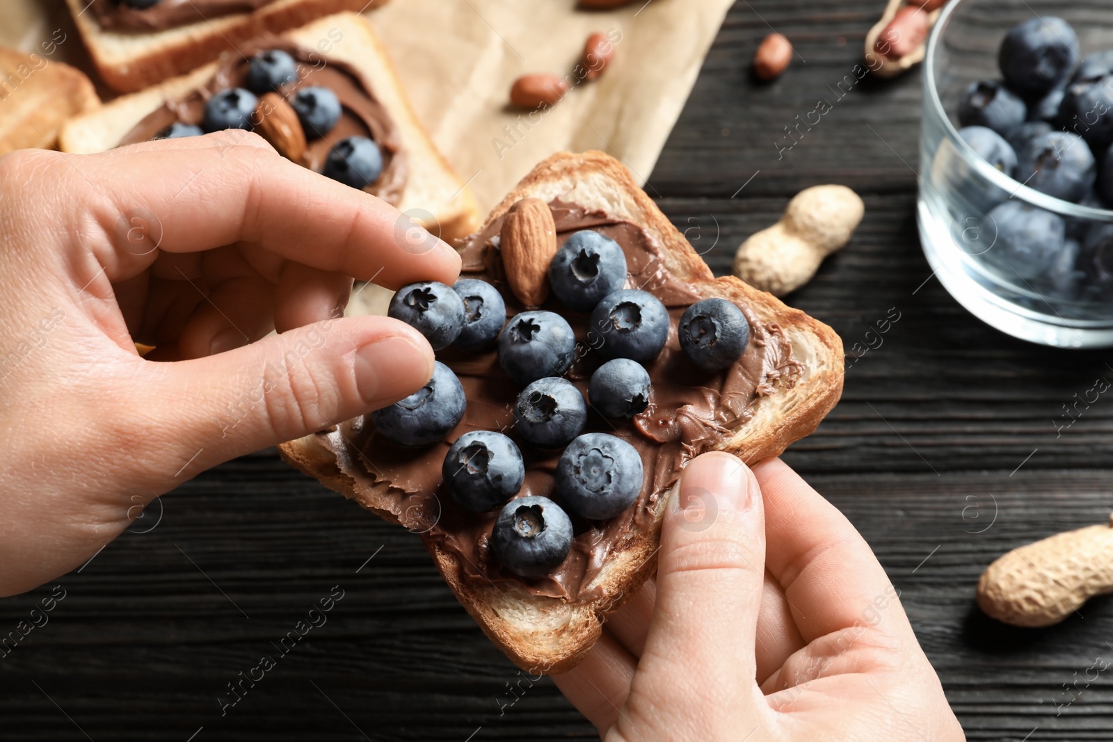 Photo of Woman holding toast bread with blueberries over table, closeup