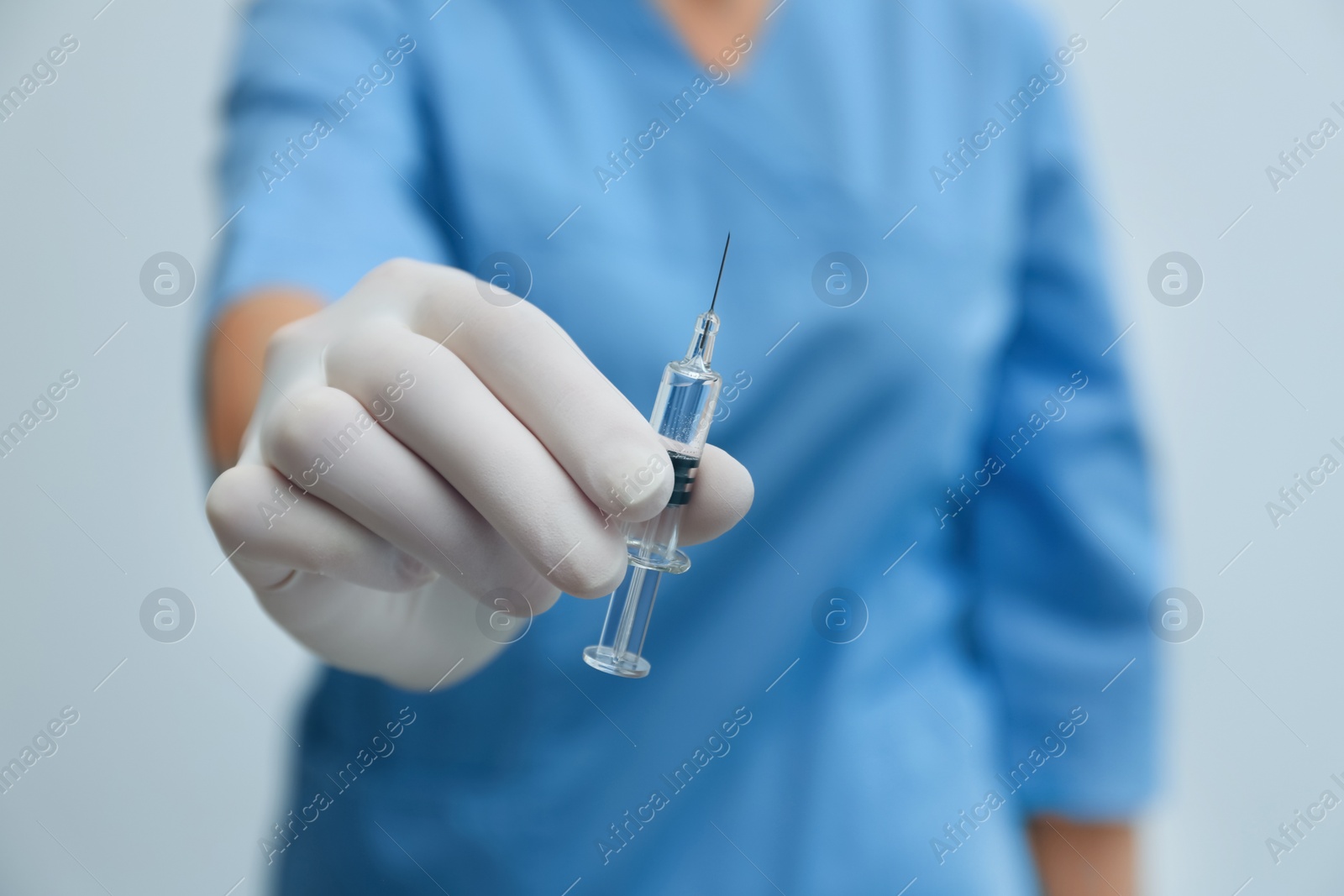 Photo of Doctor holding syringe with COVID-19 vaccine on light background, closeup