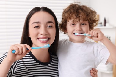 Photo of Mother and her son brushing teeth together in bathroom