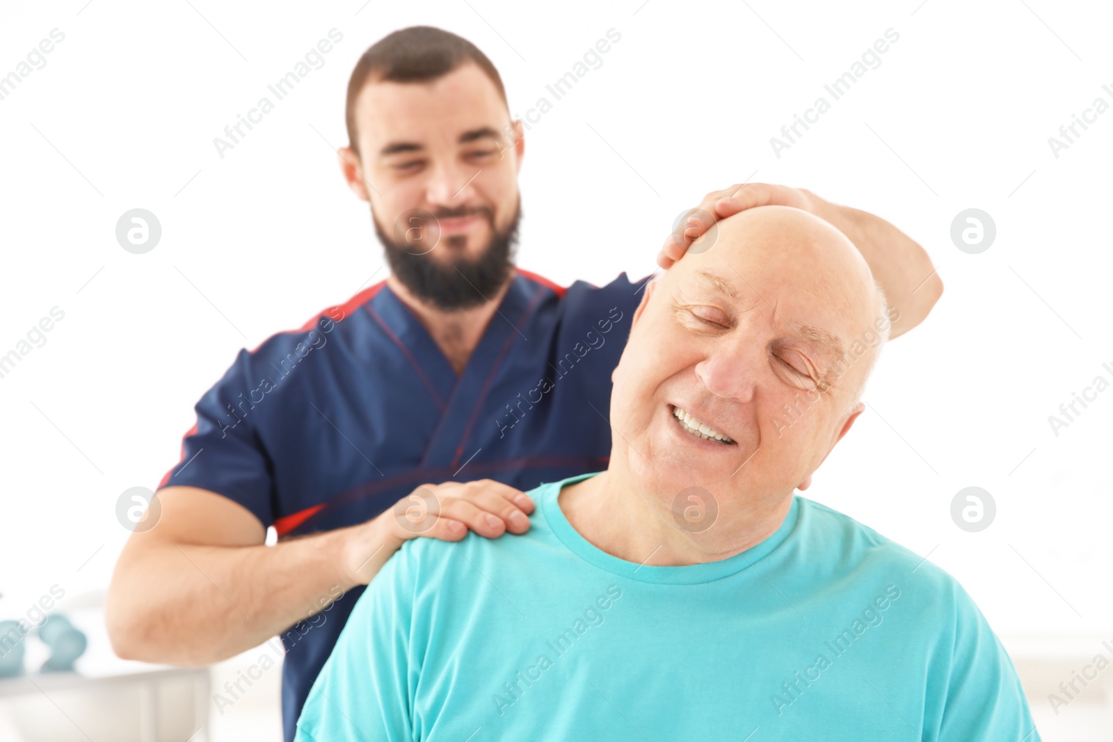 Photo of Young physiotherapist working with senior patient in clinic