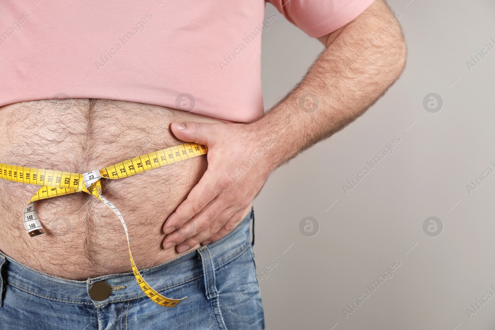 Photo of Overweight man with large belly and measuring tape on color background, closeup