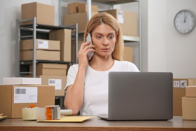 Photo of Seller talking on phone while working in office. Online store