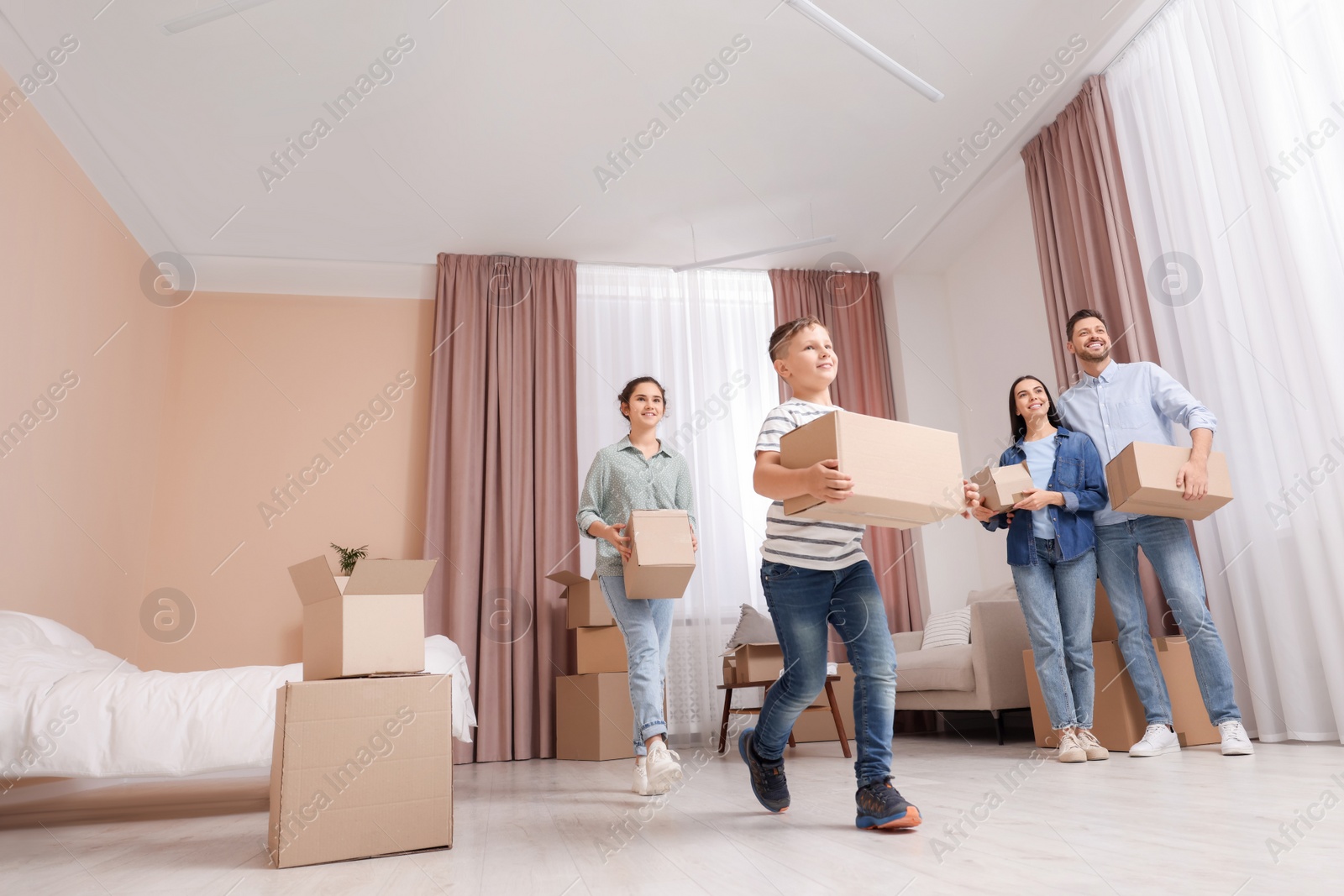 Photo of Happy family with moving boxes in apartment. Settling into new house