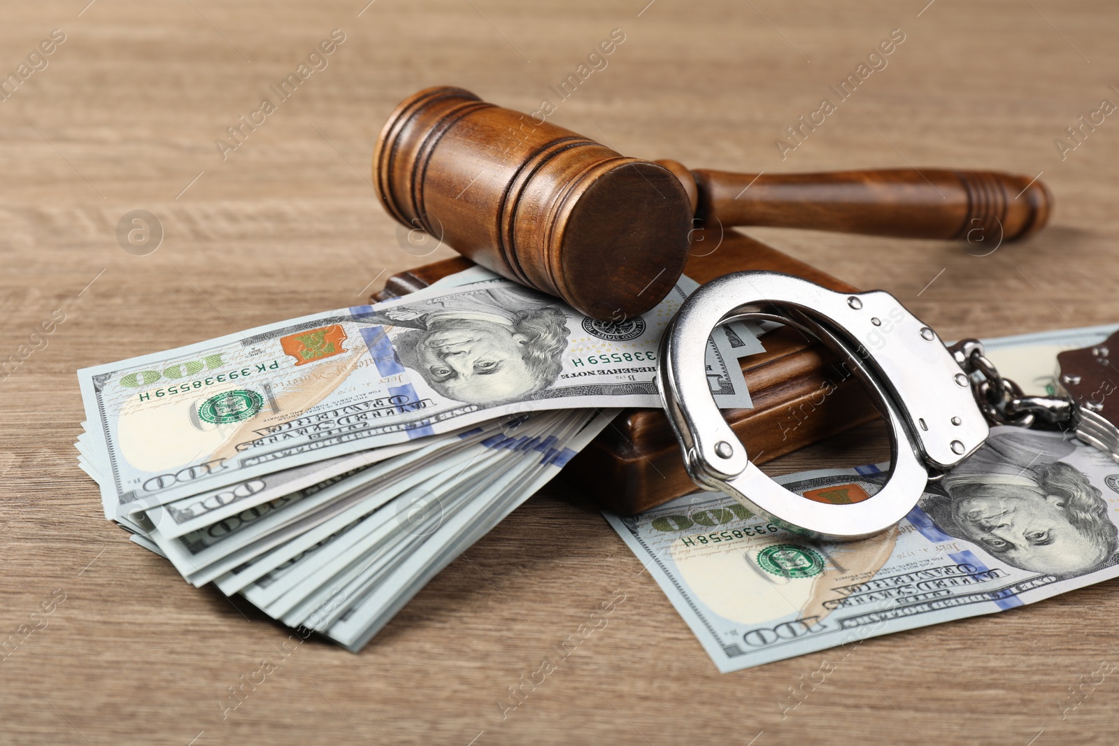 Photo of Judge's gavel, money and handcuffs on wooden table