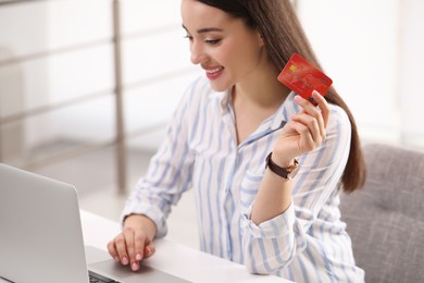 Photo of Woman with credit card using laptop for online shopping at white table indoors, closeup