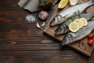 Photo of Sea bass fish and ingredients on wooden table, flat lay. Space for text