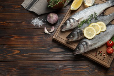 Sea bass fish and ingredients on wooden table, flat lay. Space for text