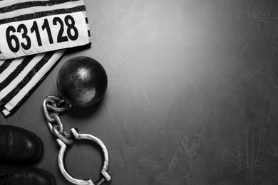 Photo of Prisoner ball with chain and jail clothes on grey table, flat lay. Space for text