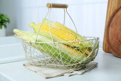 Photo of Tasty corn cobs on white countertop in kitchen