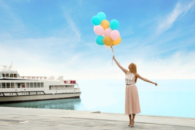 Photo of Beautiful young woman with bunch of balloons outdoors