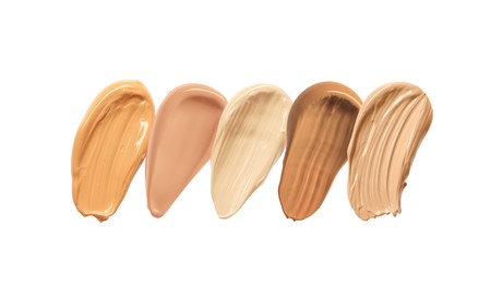 Different shades of liquid skin foundation on white background, top view