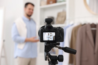 Fashion blogger showing clothes while recording video at home, focus on camera