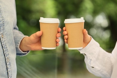 Women holding takeaway paper cups outdoors, closeup. Coffee to go