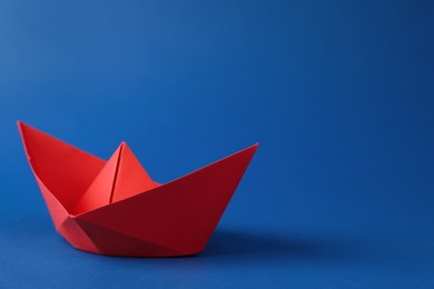 Photo of Handmade red paper boat on blue background. Space for text