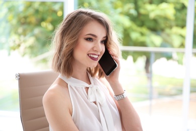 Photo of Young businesswoman talking on phone in office
