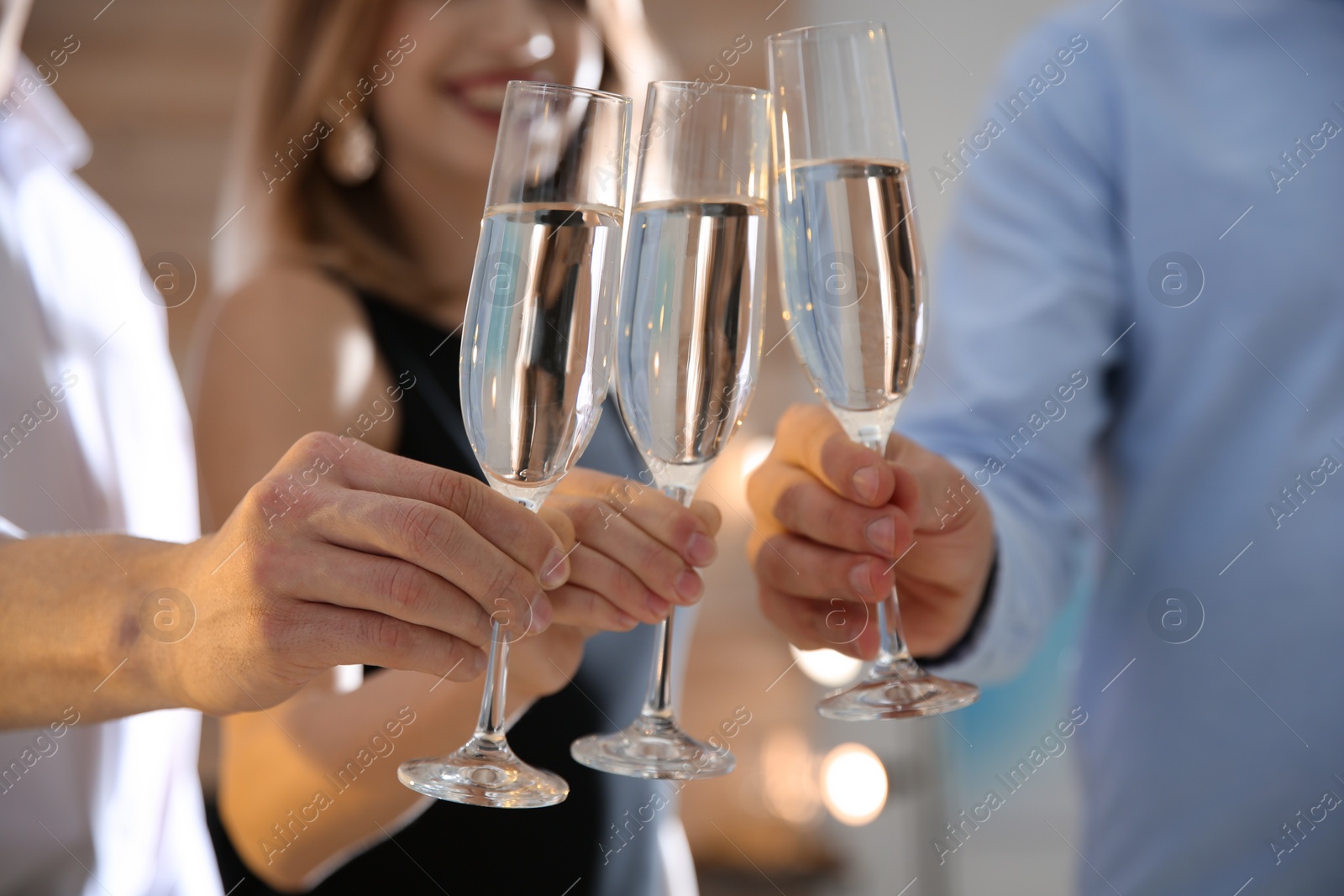 Photo of Friends clinking glasses with champagne at party indoors, closeup