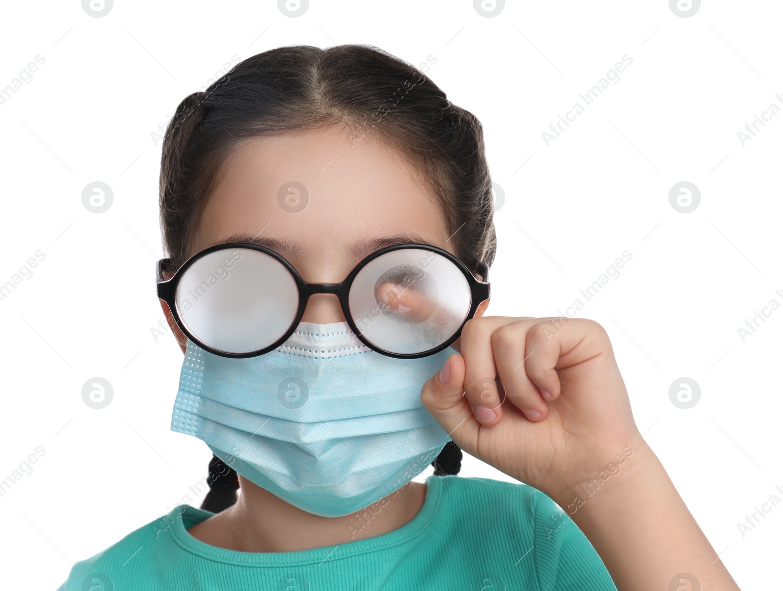 Photo of Little girl wiping foggy glasses caused by wearing medical face mask on white background. Protective measure during coronavirus pandemic