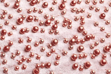 Beautiful pink fabric with golden beads as background, top view