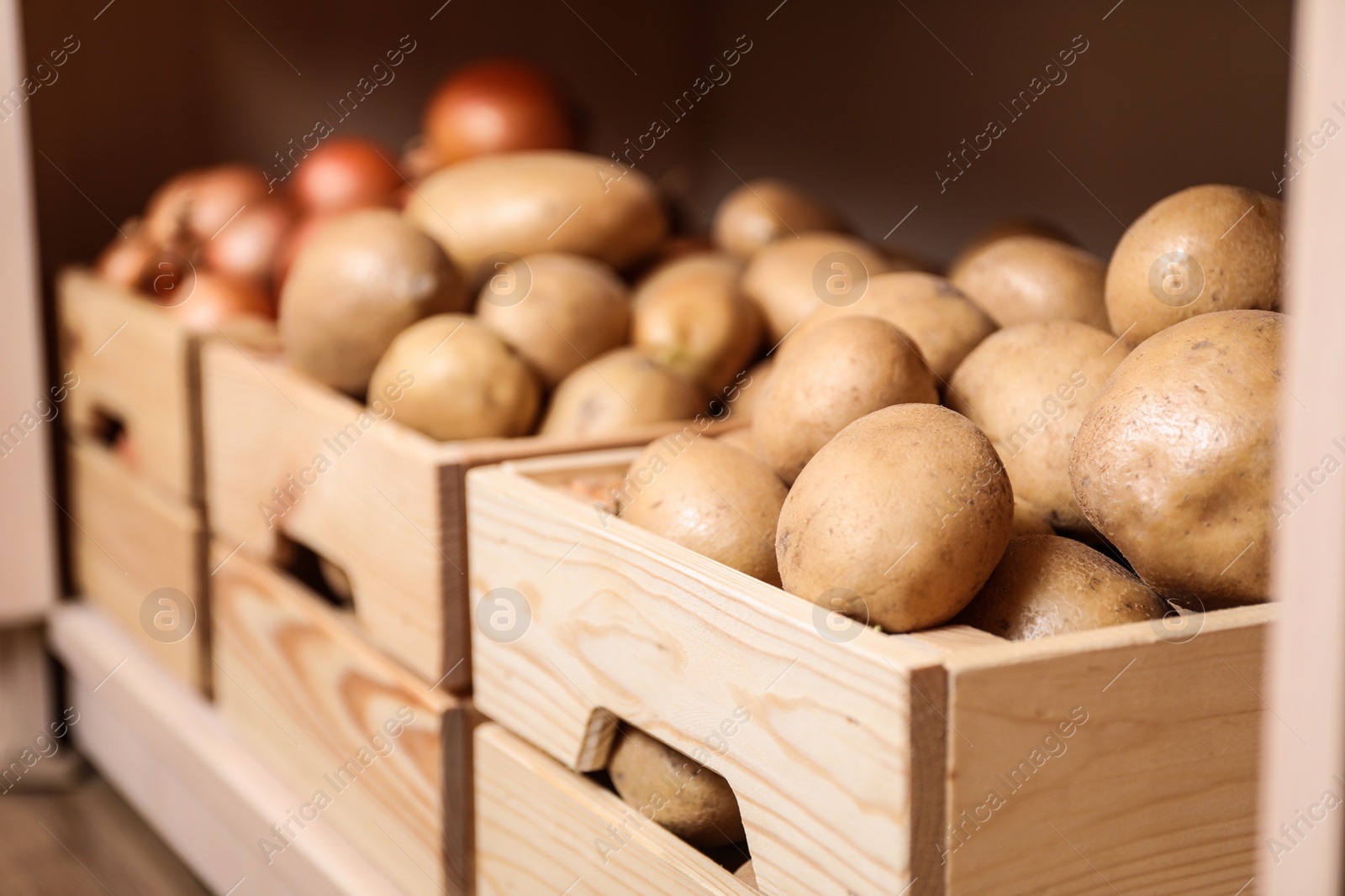 Photo of Crates with potatoes on shelf, closeup. Orderly storage