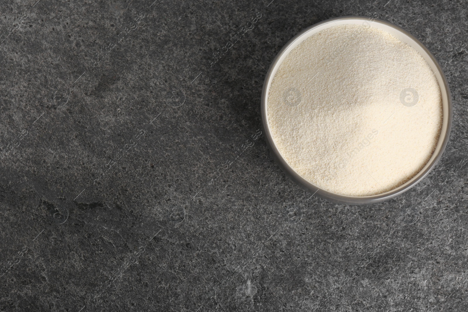 Photo of Semolina in bowl on grey table, top view. Space for text