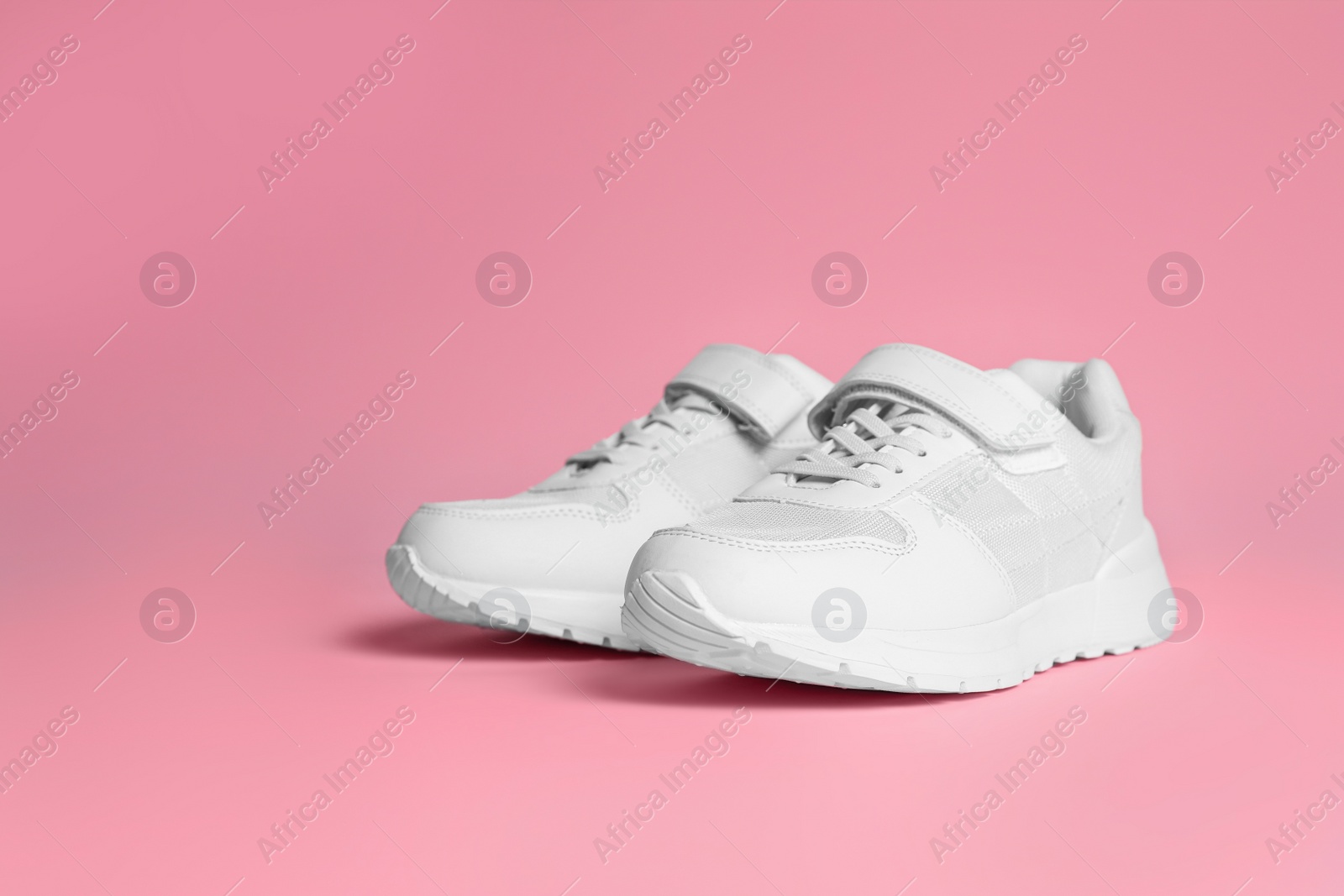 Photo of Pair of stylish sneakers on pink background