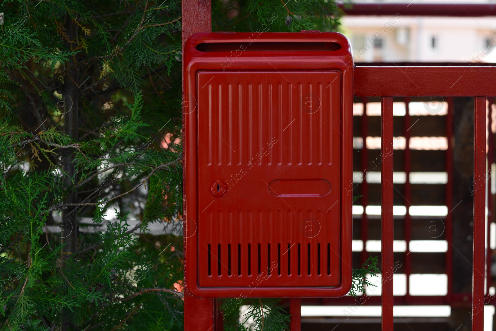 Photo of Red beautiful metal letter box near tree outdoors