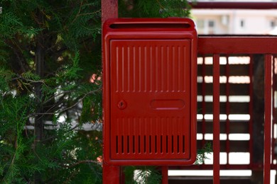 Photo of Red beautiful metal letter box near tree outdoors