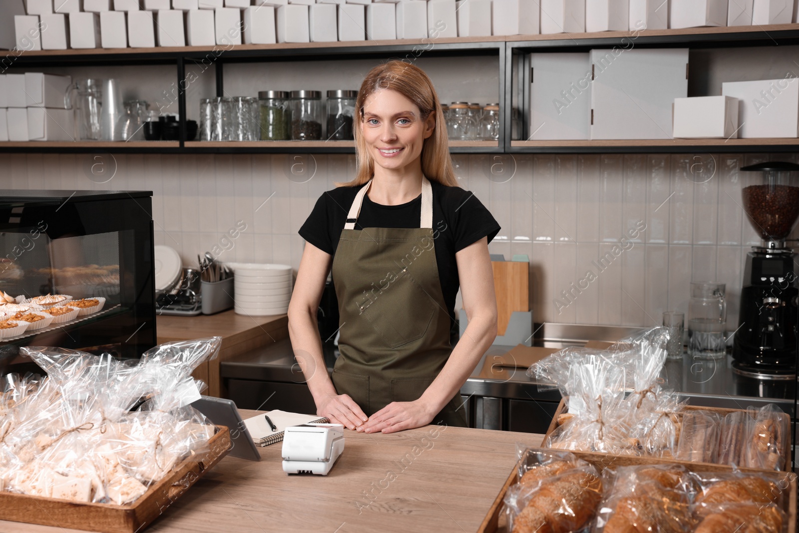 Photo of Happy seller at cashier desk in bakery shop