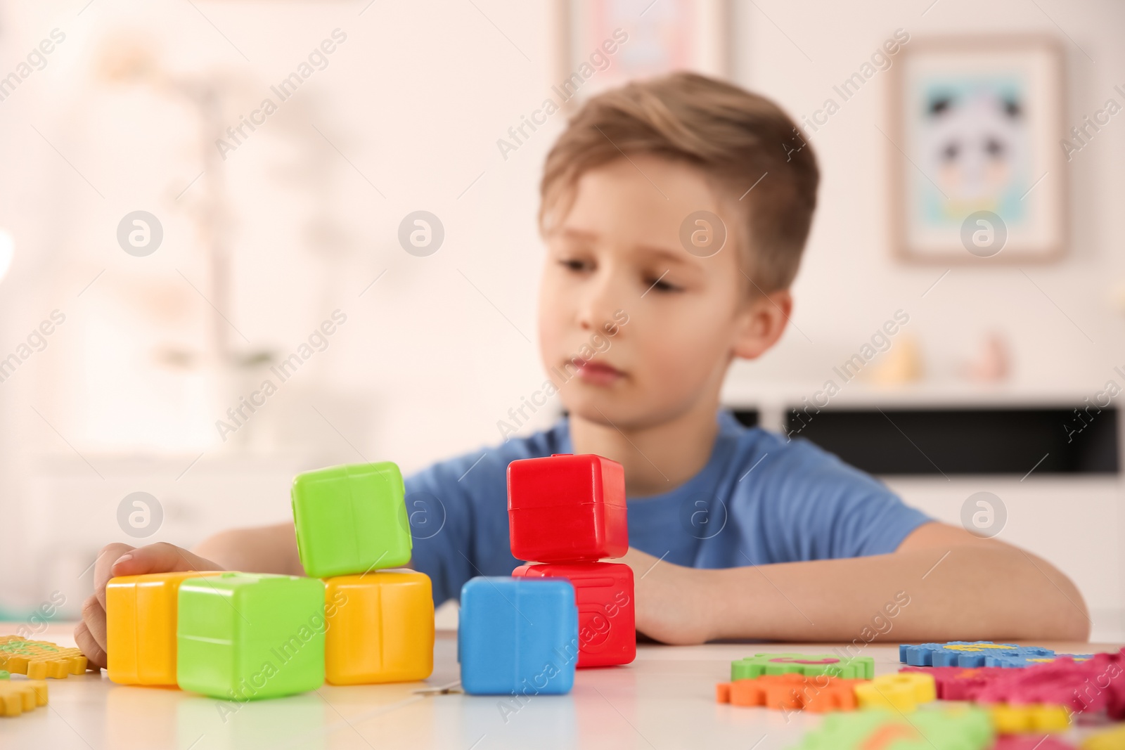 Photo of Little boy with autistic disorder playing at home, closeup of cubes