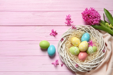 Flat lay composition with painted Easter eggs on wooden table, space for text