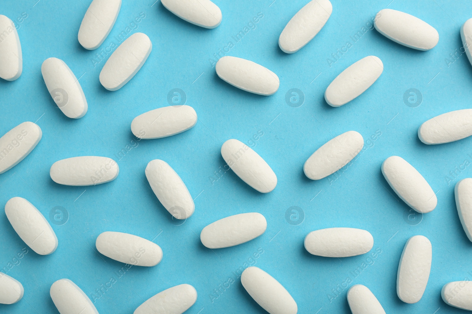 Photo of Vitamin pills on light blue background, flat lay