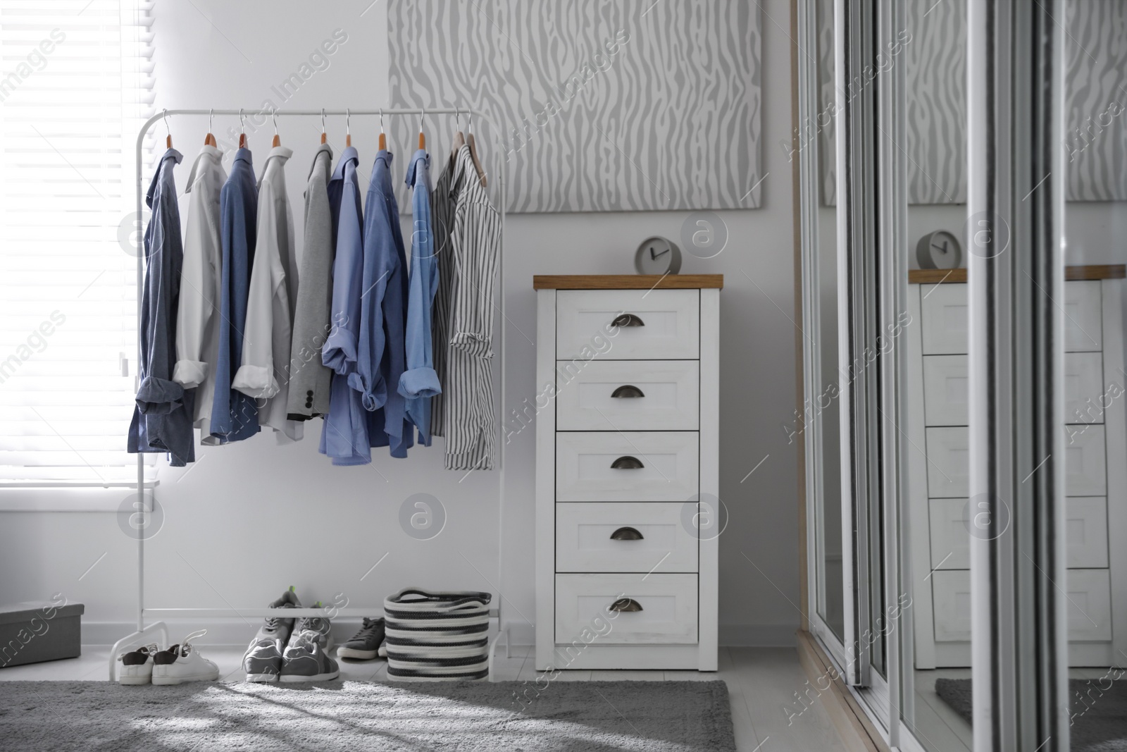 Photo of Dressing room interior with clothing rack and chest of drawers