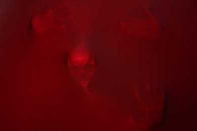 Silhouette of creepy ghost with skull behind red cloth