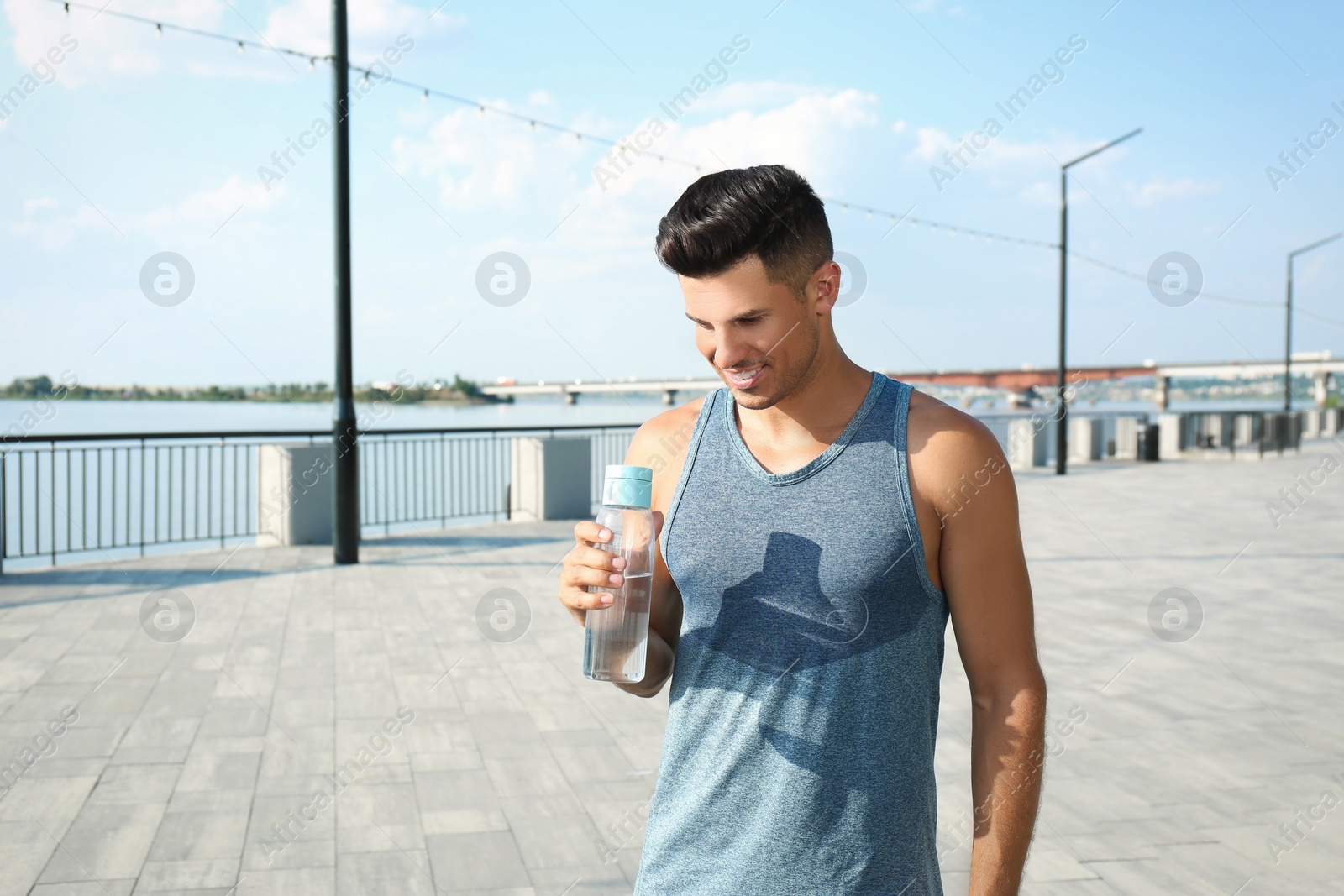 Photo of Handsome man in sportswear with bottle of water outdoors on sunny day