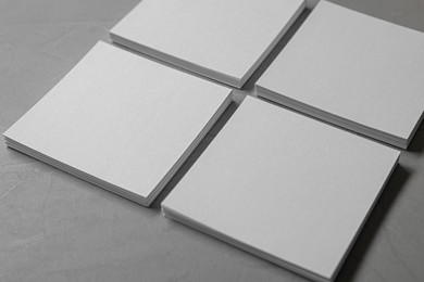 Blank paper sheets on grey textured table, closeup. Mockup for design