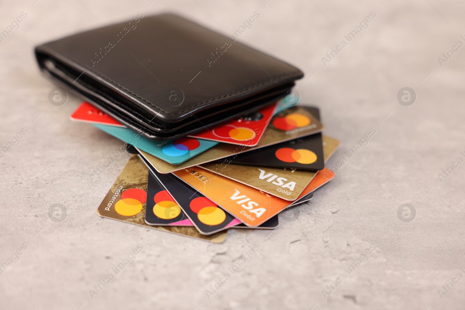 Photo of LEIDEN, NETHERLANDS - MARCH 07, 2024: Bank cards of Visa and Mastercard payment systems in leather wallet on light grey table