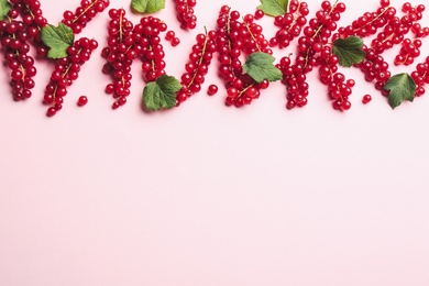 Photo of Delicious red currants and leaves on pink background, flat lay. Space for text