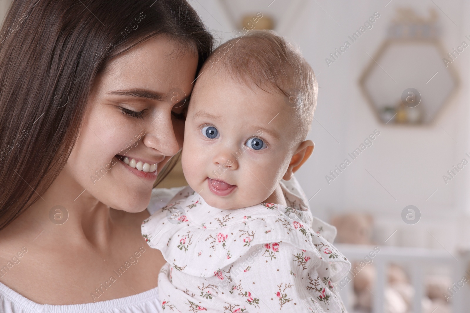 Photo of Happy young mother with her baby daughter at home, closeup