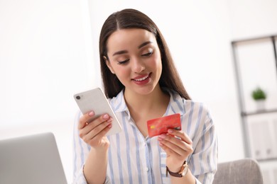 Photo of Woman with credit card using smartphone for online shopping indoors