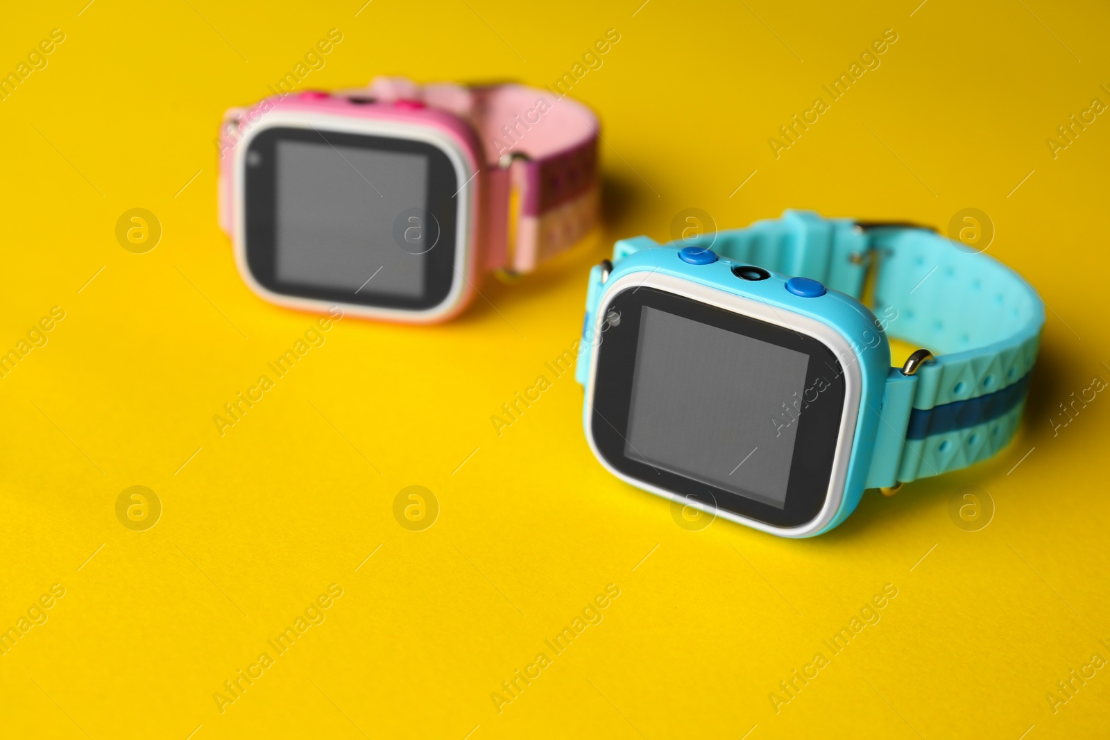 Photo of Modern trendy smart watches for kids on yellow background