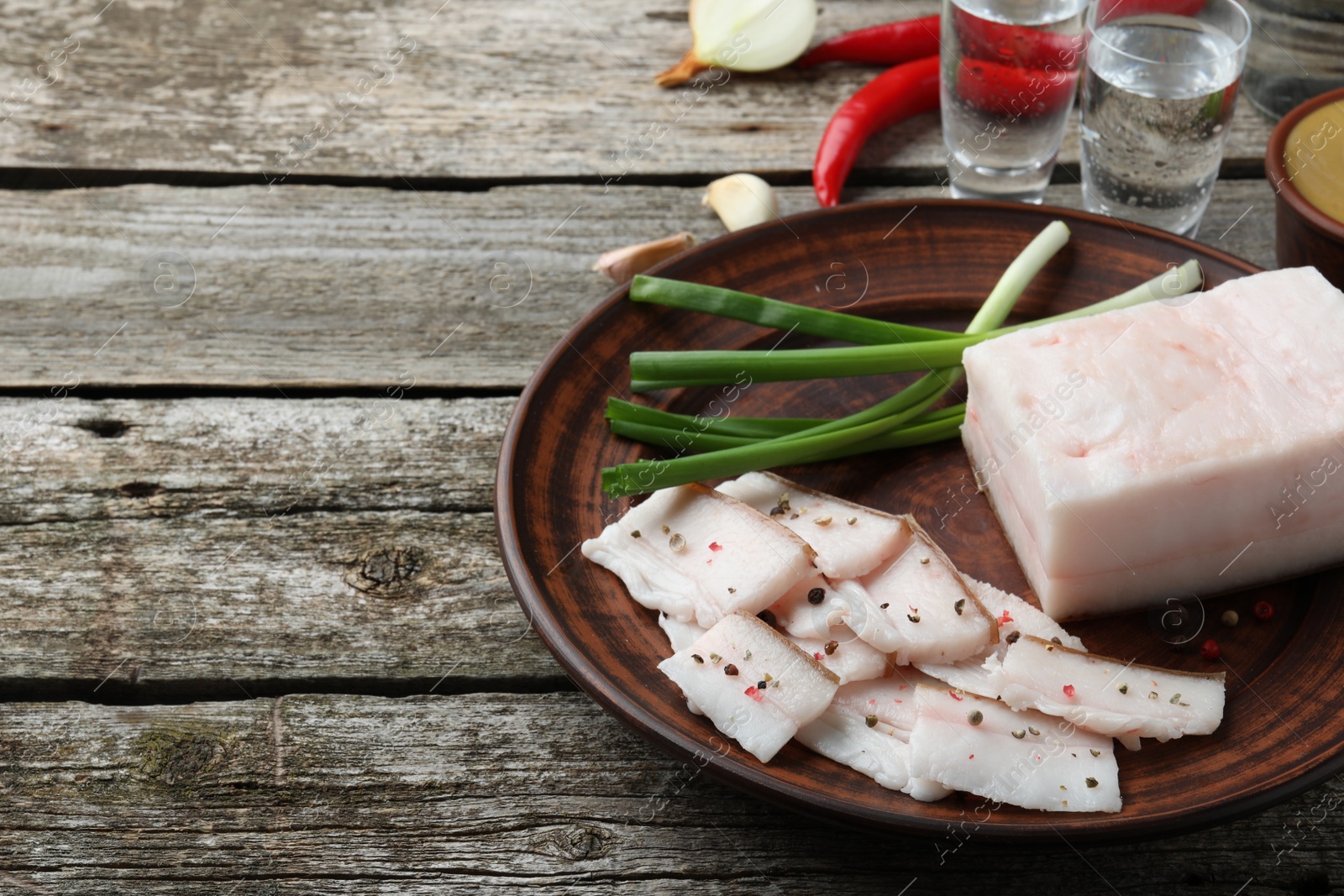 Photo of Tasty salt pork with green onion served on wooden table, space for text