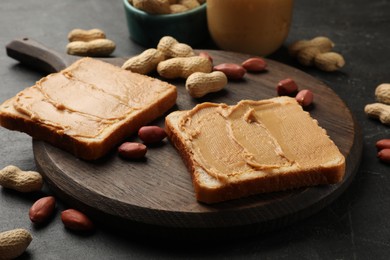 Photo of Tasty peanut butter sandwiches and peanuts on black table, closeup