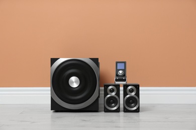 Modern powerful audio speaker system on floor near orange wall