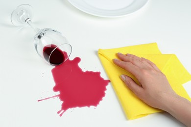 Photo of Woman cleaning spilled wine on white background, closeup