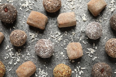 Photo of Delicious vegan candy balls and desiccated coconut on grey table, flat lay