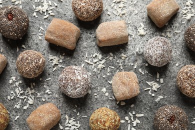 Delicious vegan candy balls and desiccated coconut on grey table, flat lay