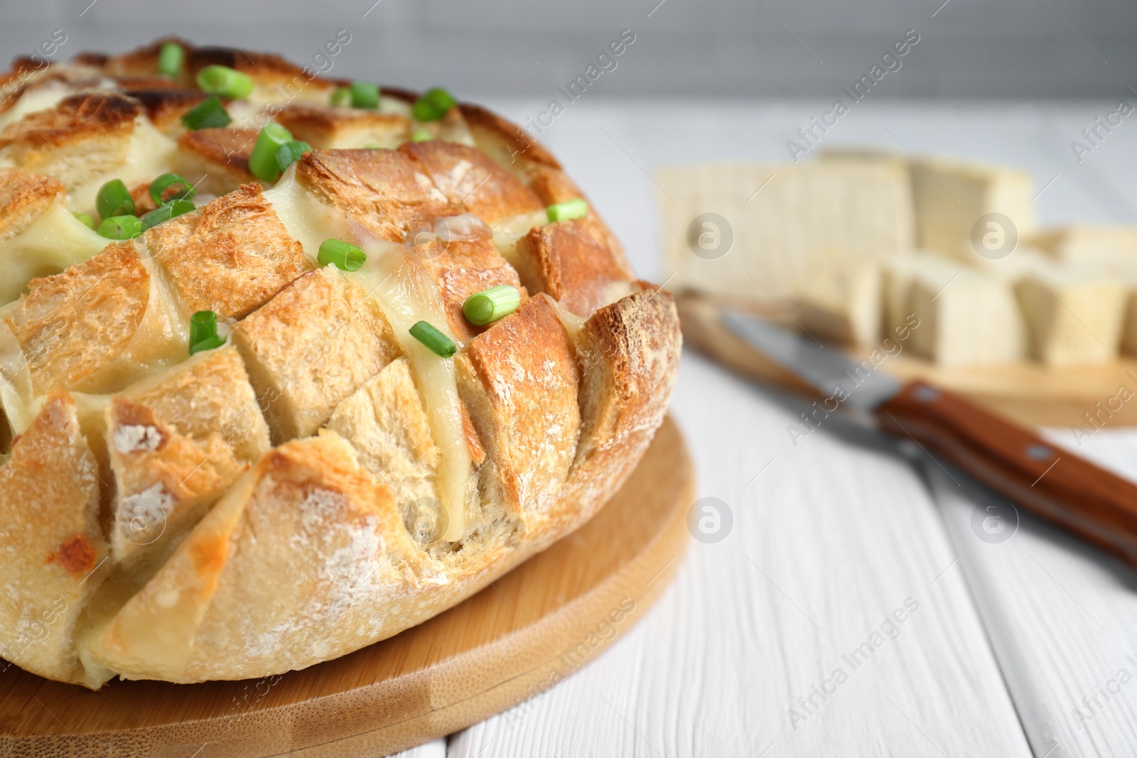 Photo of Freshly baked bread with tofu cheese and green onions on white wooden table, closeup. Space for text